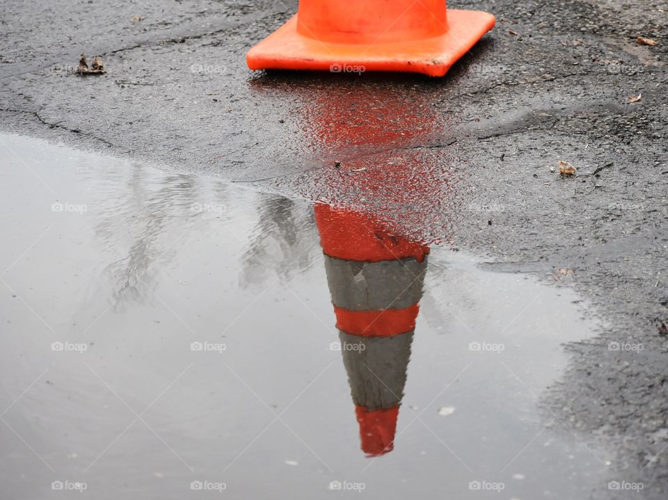 Orange traffic cone with puddle reflection