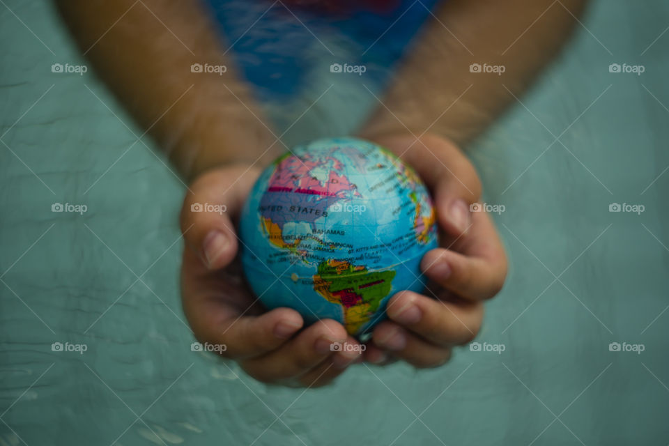 overhead looking down on hands holding world sphere North and south America continent