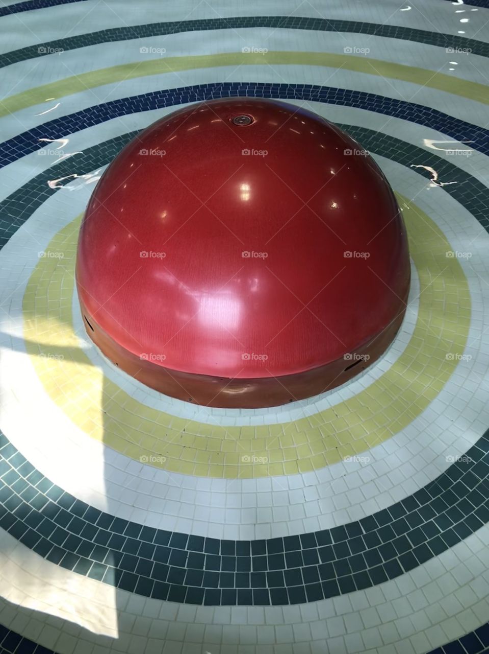 Colourful tiles in a circular formation in a water pool