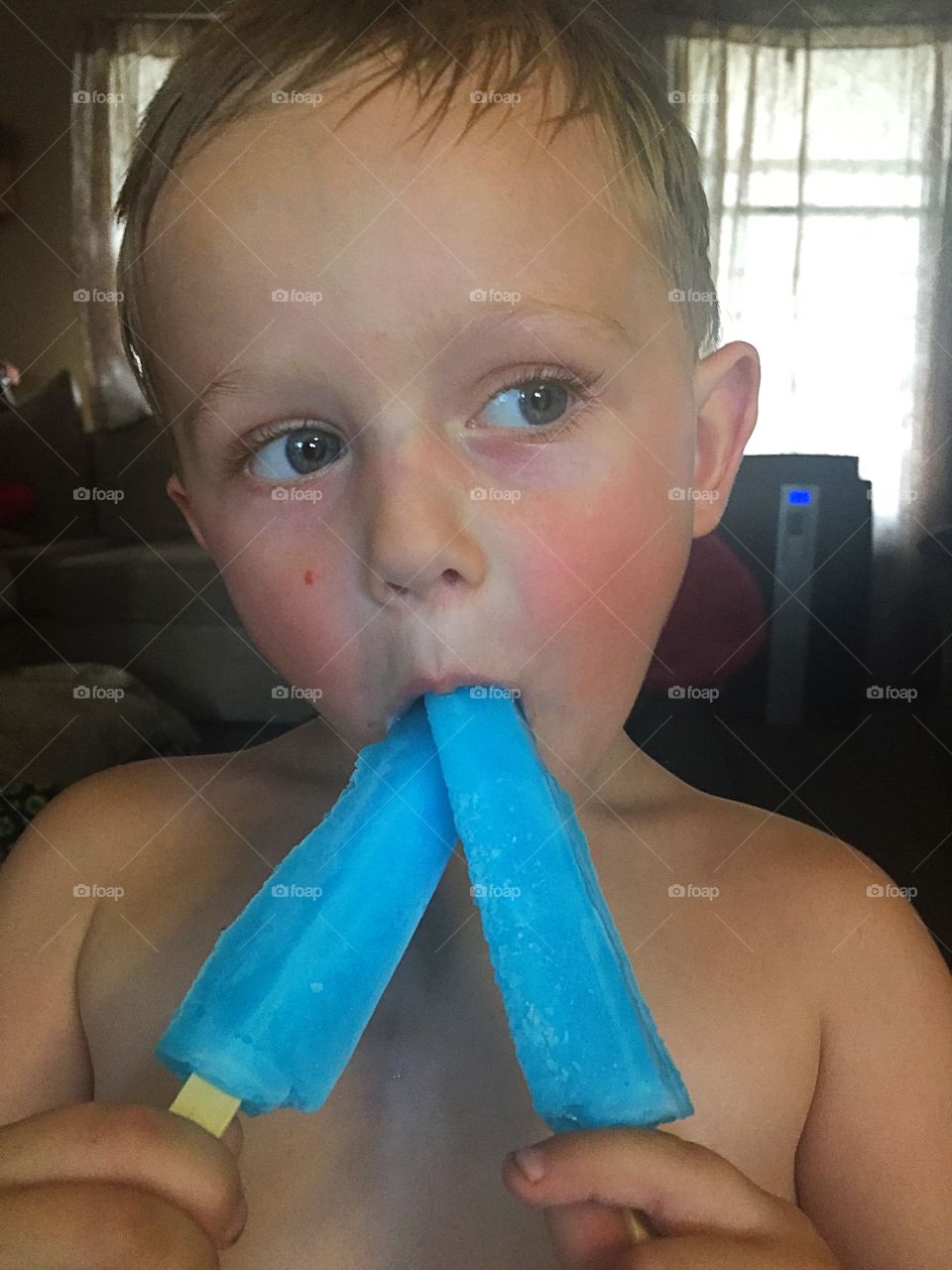 Little shirtless boy eating ice-cream