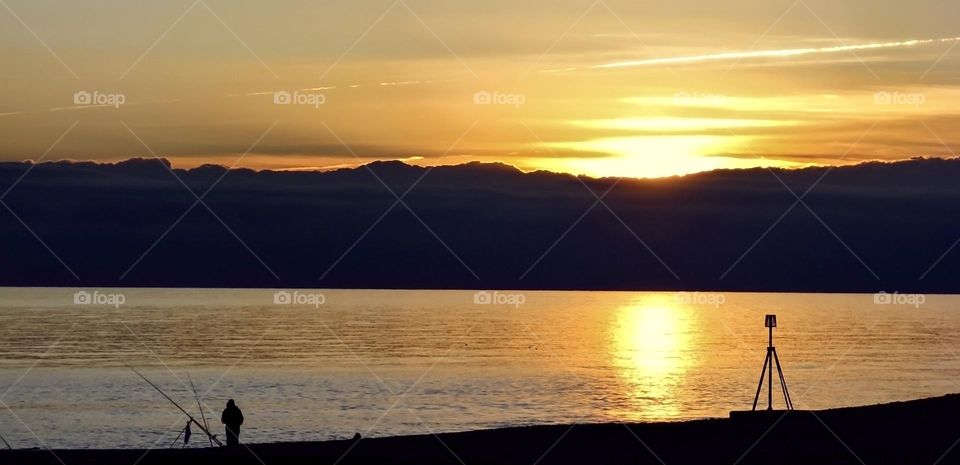 A fisherman in on the beach at sunset at St Leonards on sea, UK