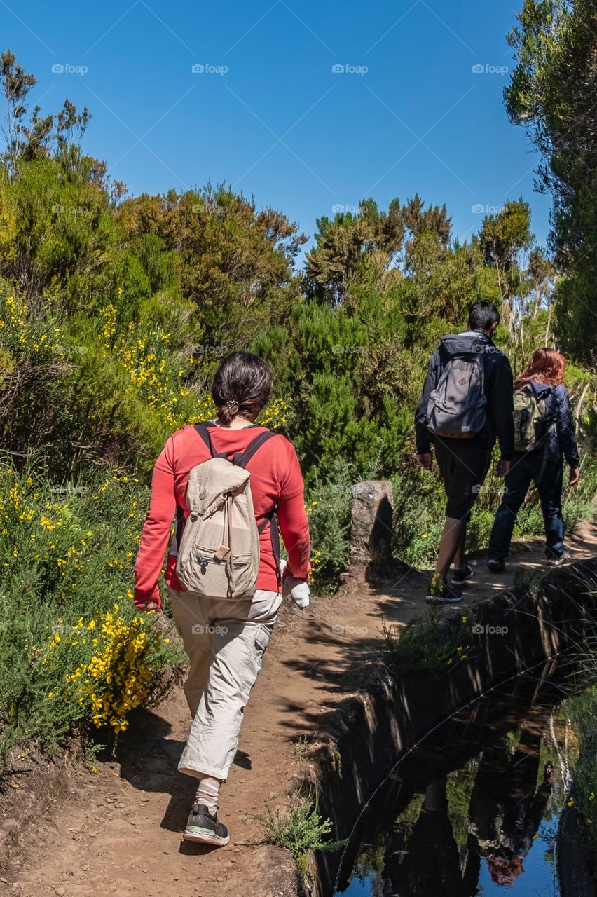 Three people walk with a backpack on their backs