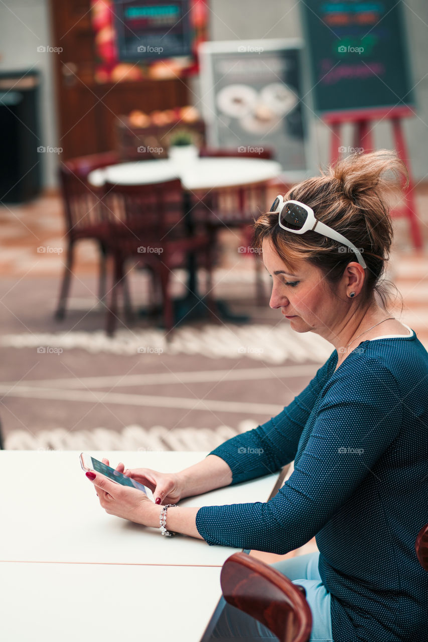 Young woman using mobile phone sitting by a table in cafe