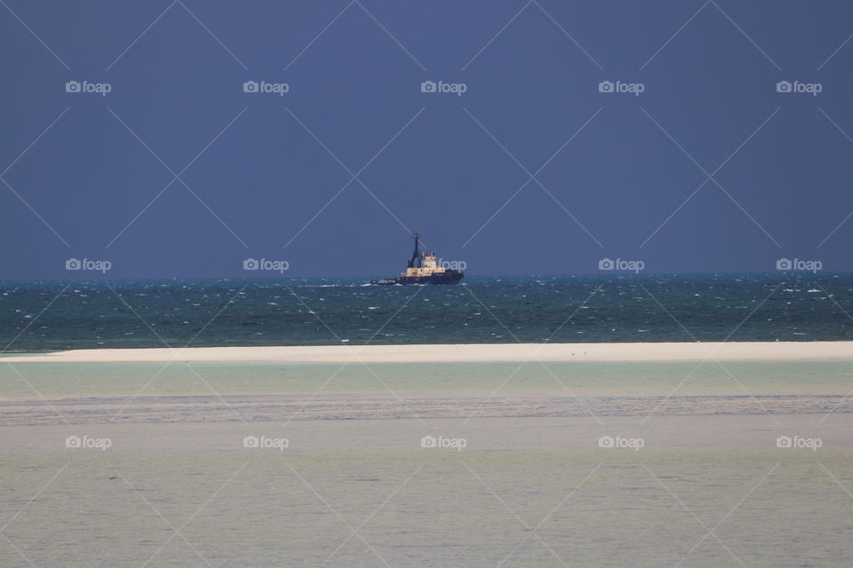 Tugboat on the ocean horizon in storm at low tide minimalist 