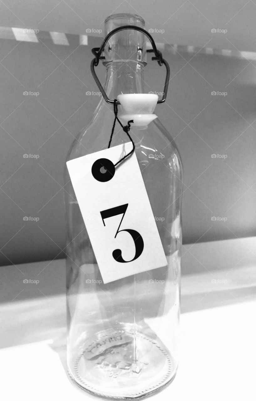Bottle #3. A large glass bottle with a number 3 tag on it.