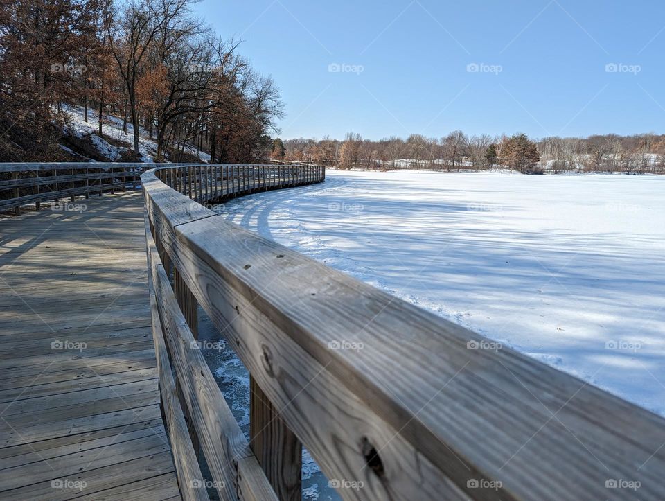 wooden bridge curve on frozen lake in early spring