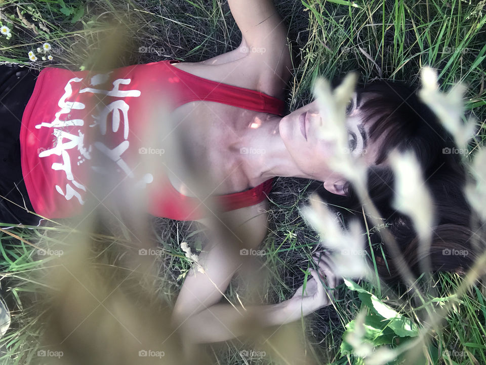 Girl lounging in green grass field during lazy summer days 