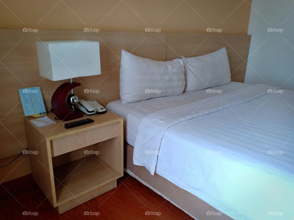 king sized bed room with side bed lampu and table and phone. wallpaper with wooden design.