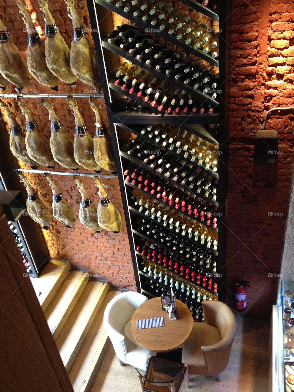 Spanish Jamón - Ham hanging on the wall in a restaurant and bottles of wine