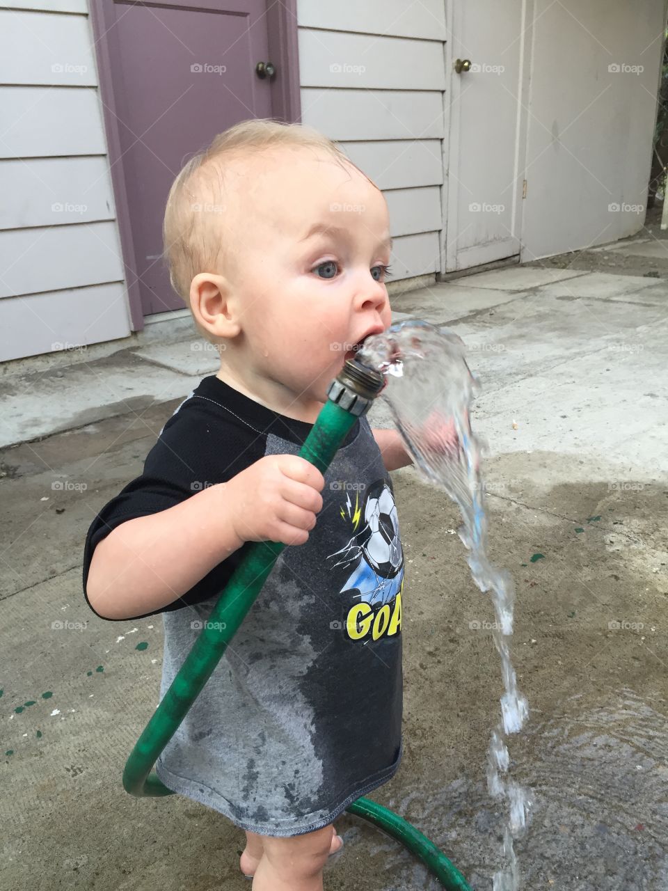 Small kid drinking water from pipe