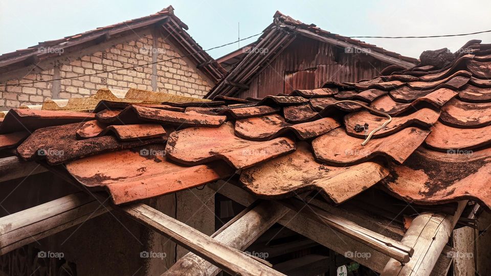 View of old school roof tiles made of clay on the roof of a house with a rickety bamboo frame, clay tiles that are generally installed on houses in Indonesia.
