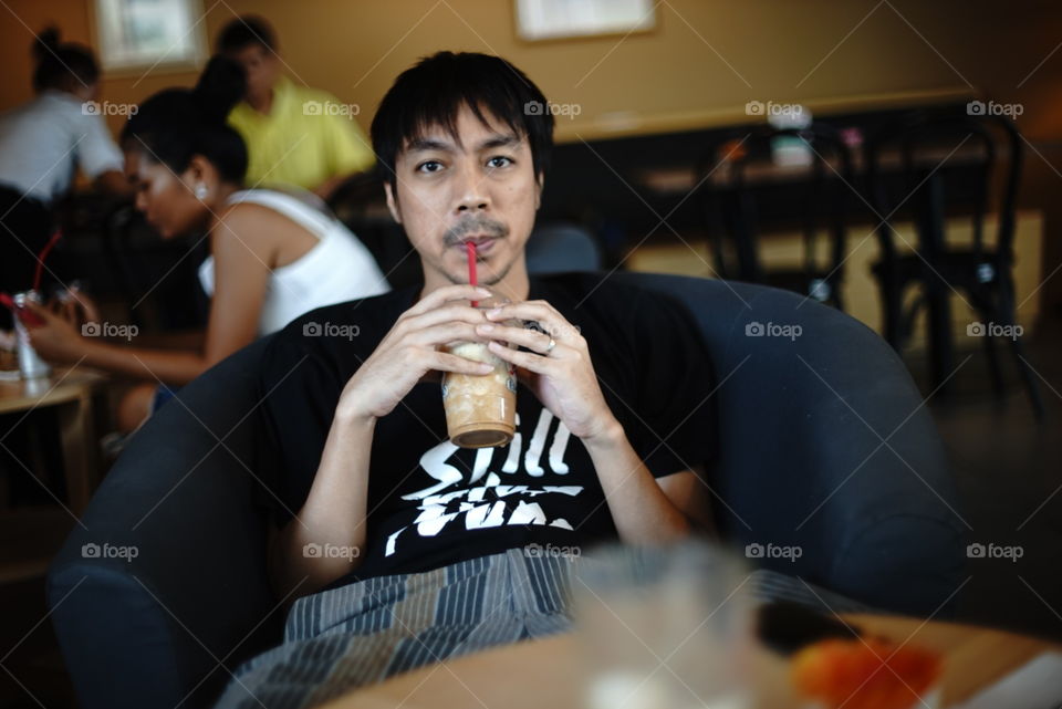 Asian guy having cold coffee in cafe