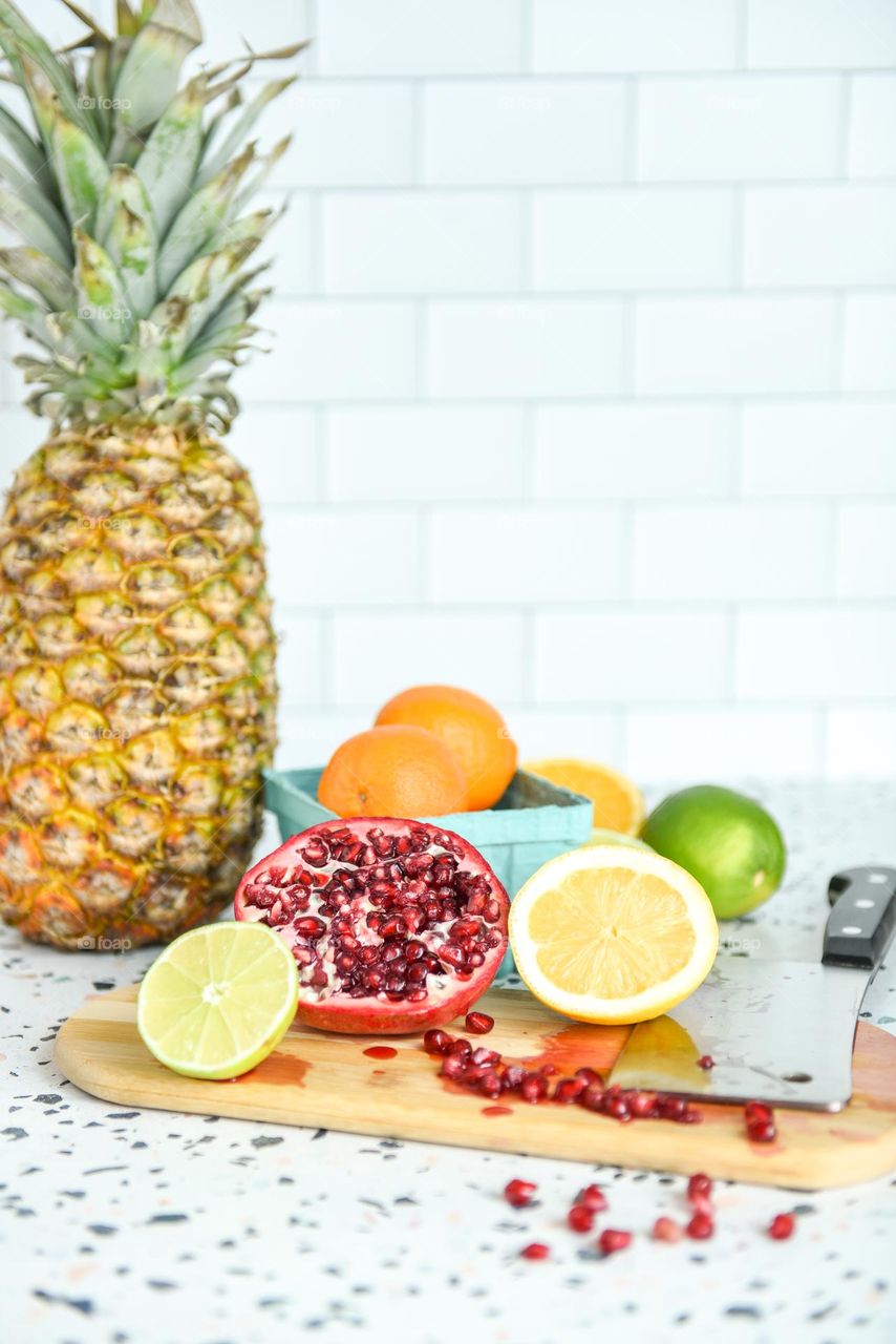 Summertime citrus and fruits on a cutting board with a knife 