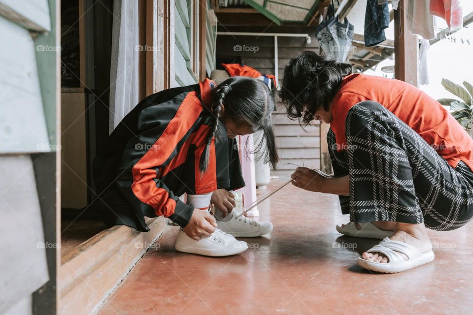 It's time to go back to school, a mother helping her daughter to tie her shoelaces.