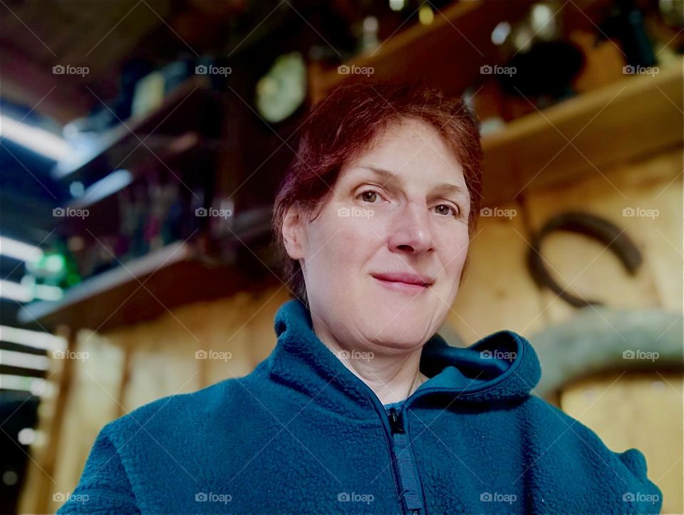 This lovely young lady is spending some quality time at „Ron’s Whiskey Lounge“, a rustic „Country Western“ style wooden shed with equestrian decor such as leather holsters, saddles and a miniature sculpture of a horse. 2024. Hypnotic Productions