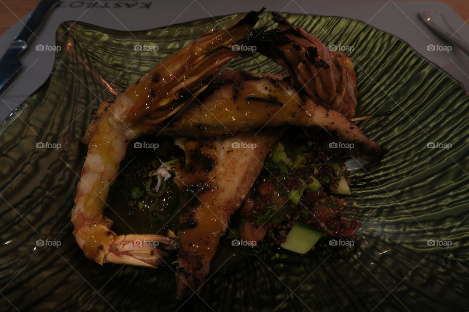 Whole shrimp cooked with grilled fish fillet served with sauce and green vegetables.