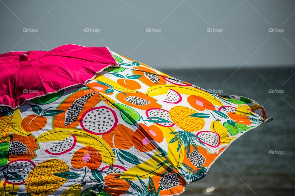 tropical fruit print beach umbrella on a warm summer day at the beach