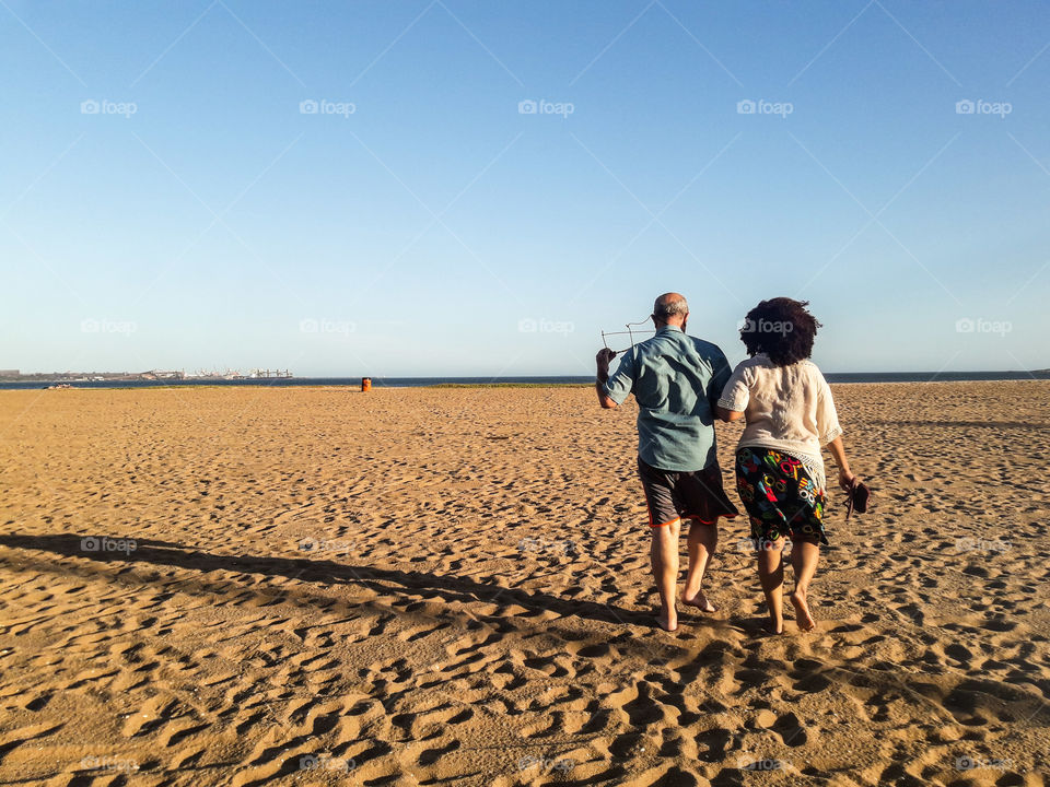 Casal de idade caminhando na praia
