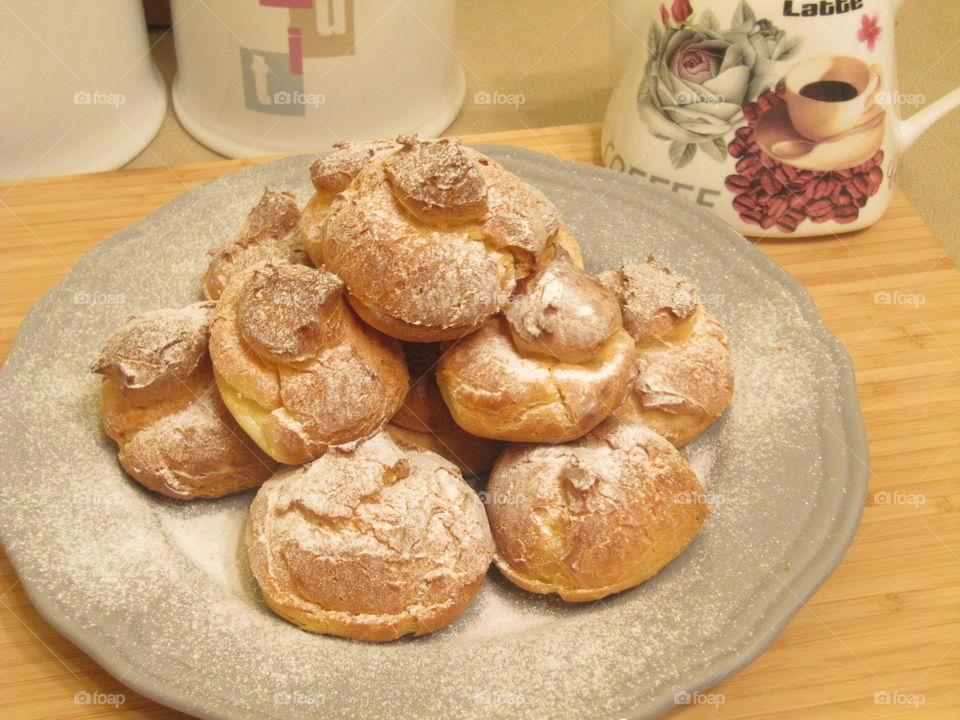 Profiteroles with white sweet cream with orange taste and a little bit of sugar in the top