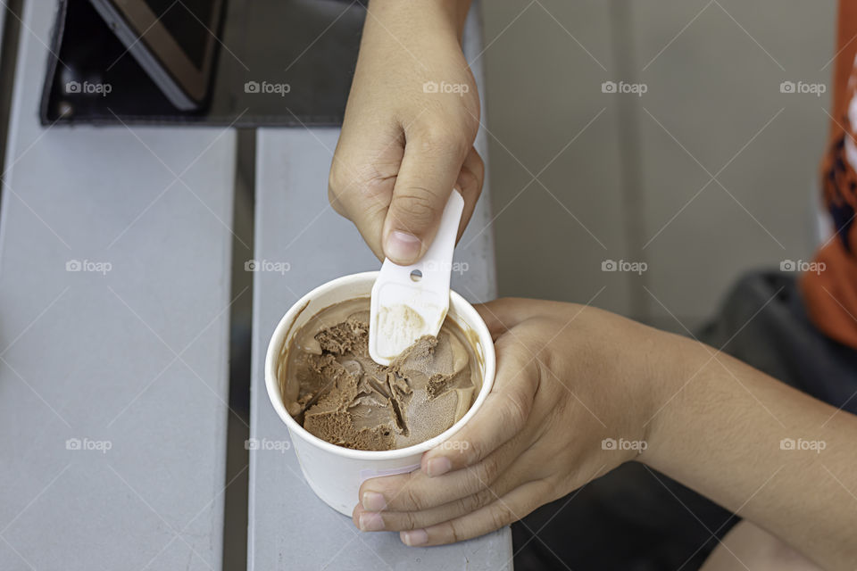 Hand boy holding the spoon Ice cream scoop in a cup.