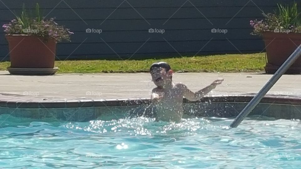 Boy splashing water in swimming pool