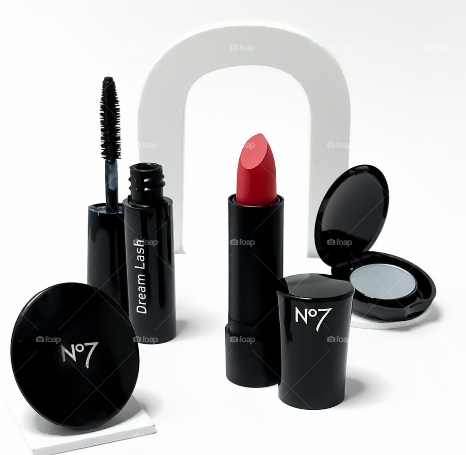 Collection of Boots No7, black cased cosmetics against white background which arch over red lipstick 