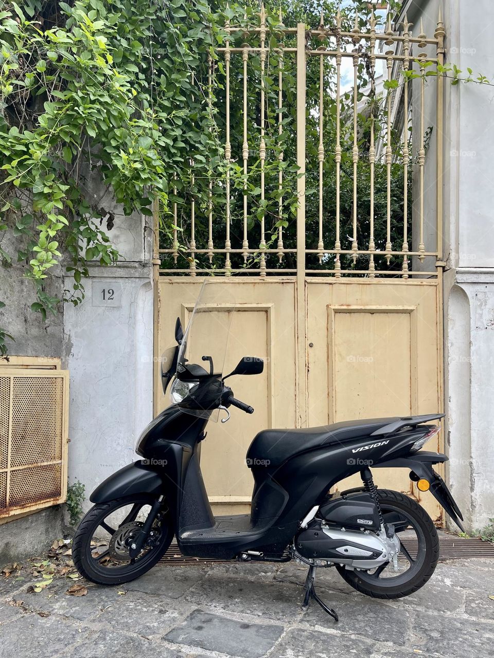 Black scooter near beige gate outdoor 