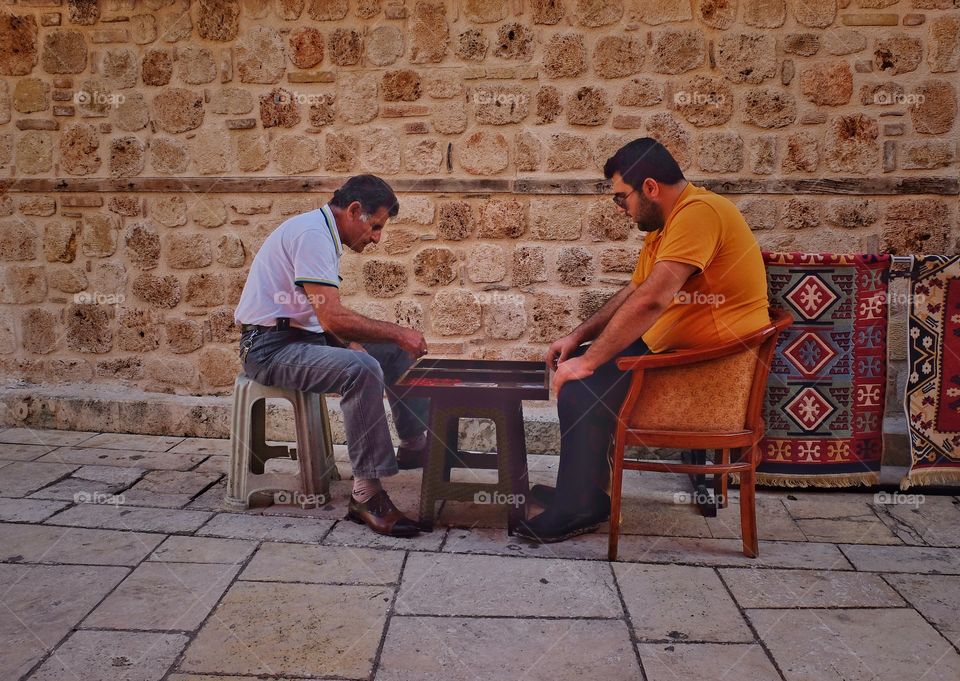 Gamers. 
Took this picture in Antalia, Turkey. Went for a walk in old part or the city and noticed those two. Decided that it could not a bad street are shot. Those men are playing a backgammon. 