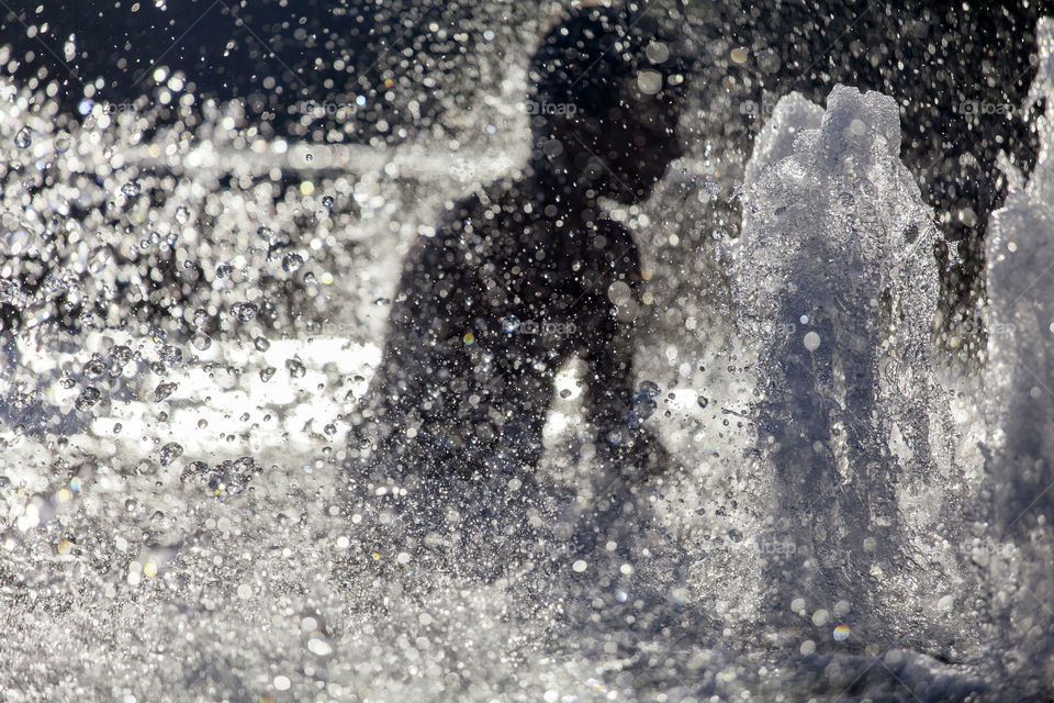 Silhouette of the boy having fun in a fountain