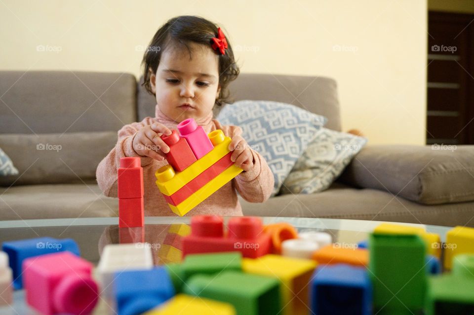 little girl playing rectangular colored constructions