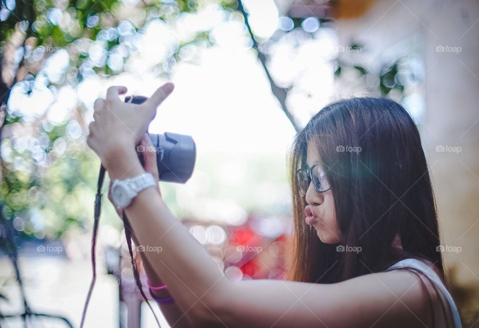 Asian girl taking selfie using camera