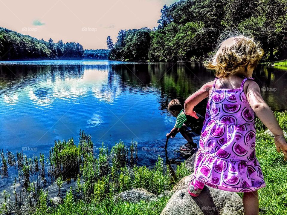 A beautiful morning with my children spent at a park which contains a gorgeous clean lake. My son kneels down to get a clear view of what what fish are swimming near the lake's edge while my daughter walks back and forth discovering natural beauty.