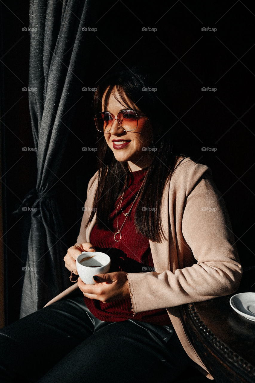 Beautiful brunette girl hold cup of coffee and smile on street cafe