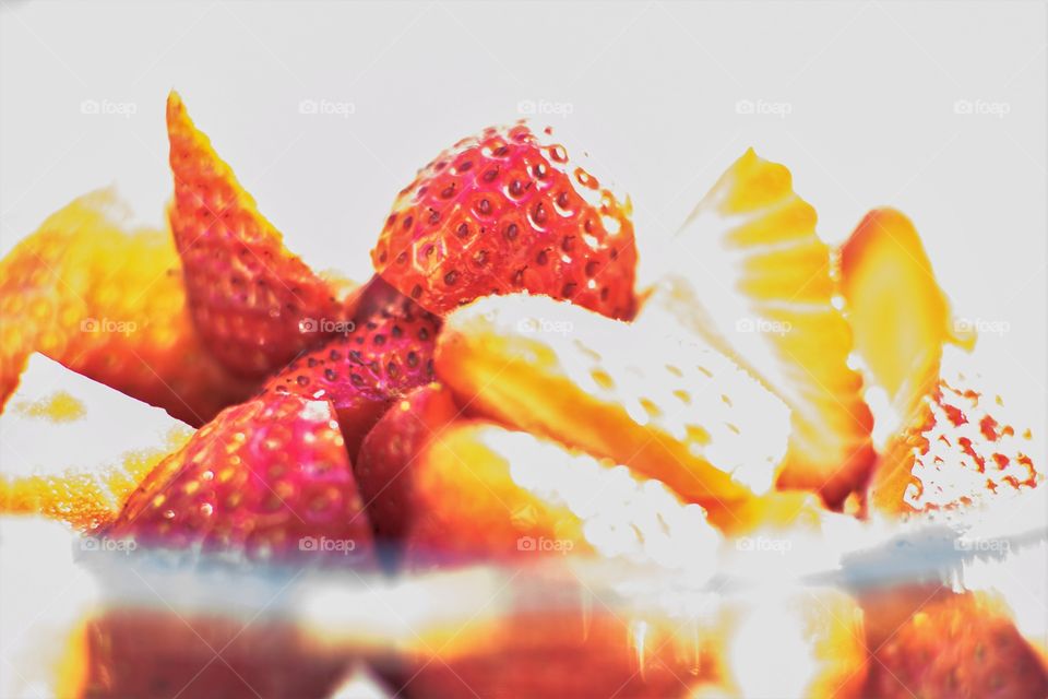 Portion of bowl of strawberries with some overexposure in direct sunlight