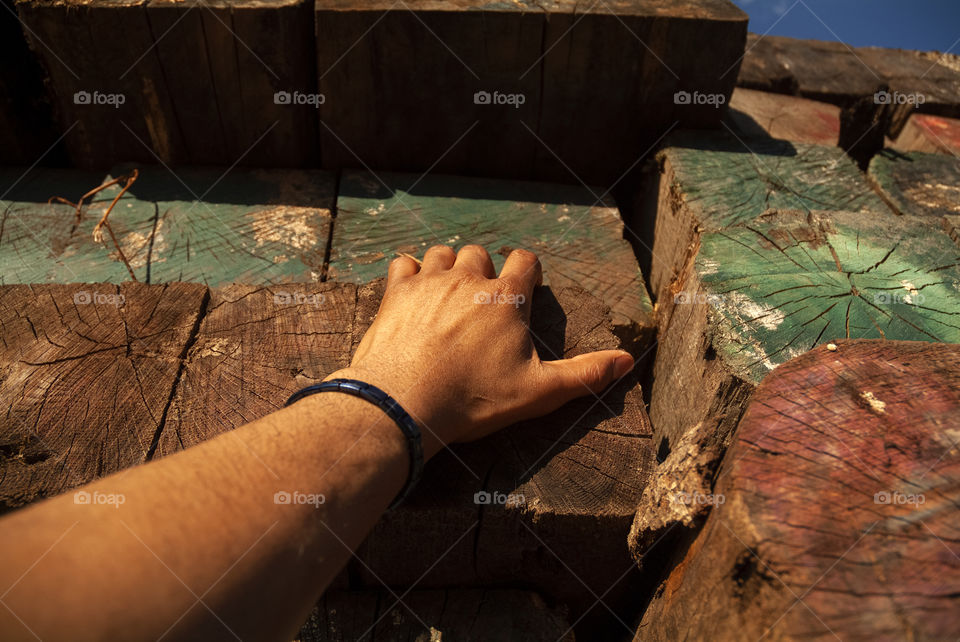 A first person perspective of a man climbing his way up a pile of multicolored timber.