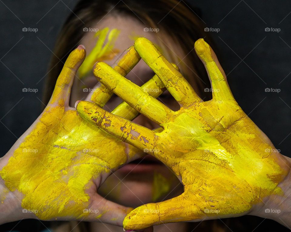 Paint the world yellow; Woman with painted hands in a dramatic setting