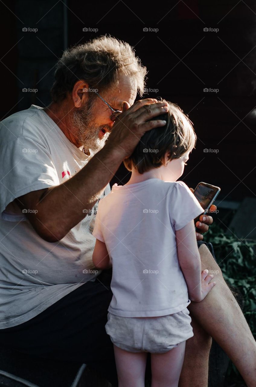 Grandfather and granddaughter communicate with someone via video link.