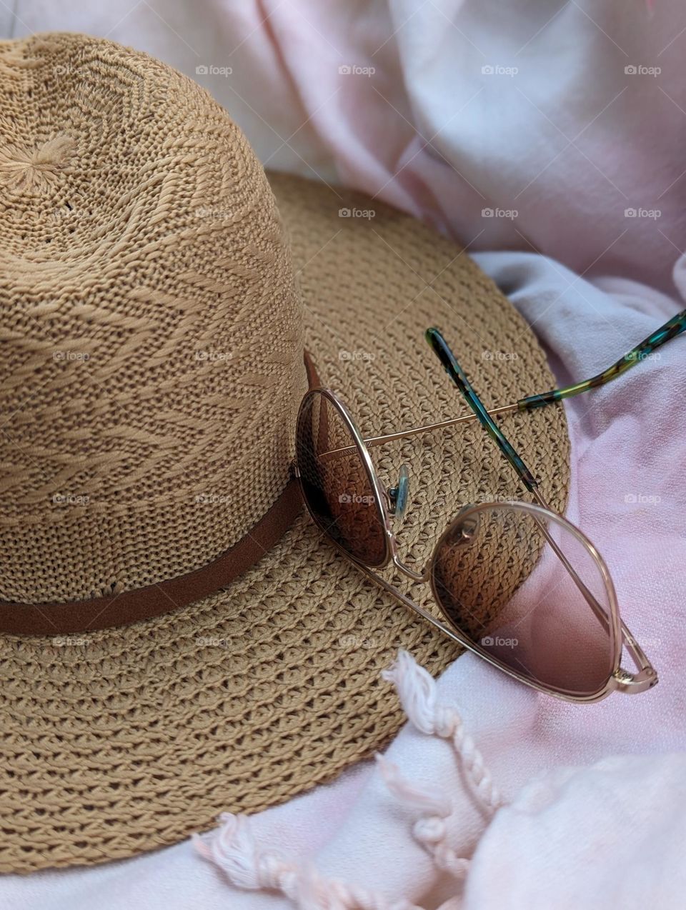 cool travel essentials Sun hat and aviator sunglasses with a pink fringe beach towel ocean beach vacation vacay