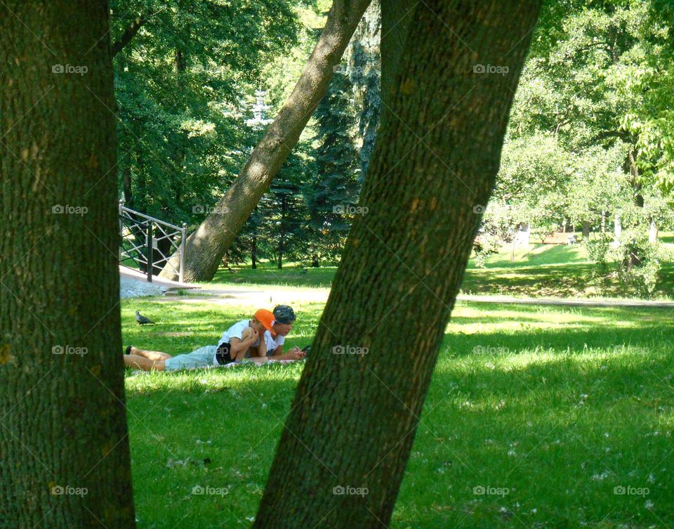 Father and son lie on the green grass in the park