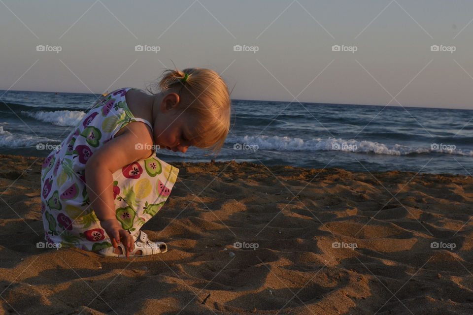 Two tear old girl playing on the beach at sunse on their family holiday in Turkey.