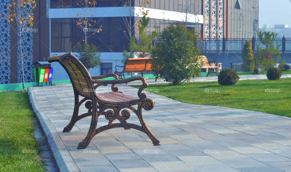 beautiful park bench in a resting place on a sunny day treacherous bench middle asia lawn and trees autumn empty bench