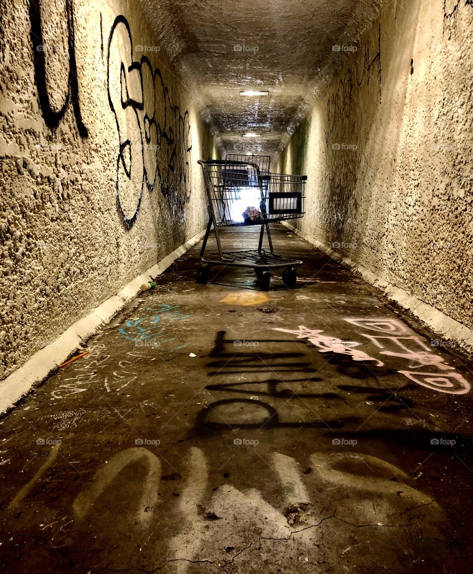 Abandoned shopping cart in a dingy tunnel filled with graffiti in Los Angeles CA 6.12.2020