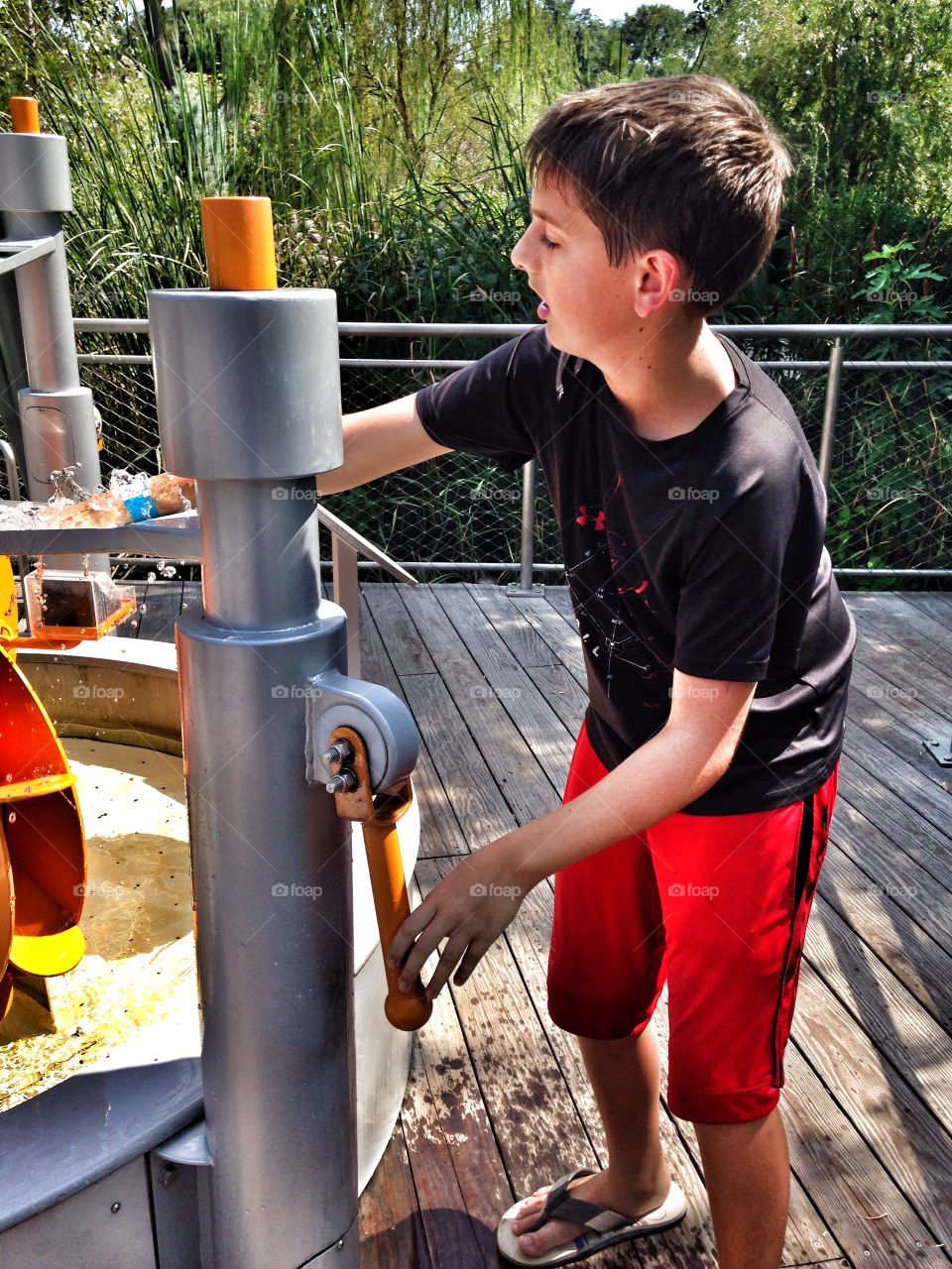 Pump it up. Boy pumping water at an outdoor exhibit