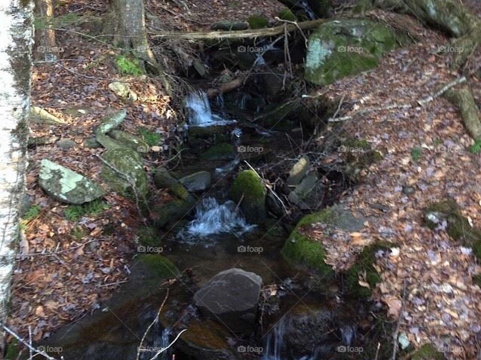 water falling down rocks on side of hill