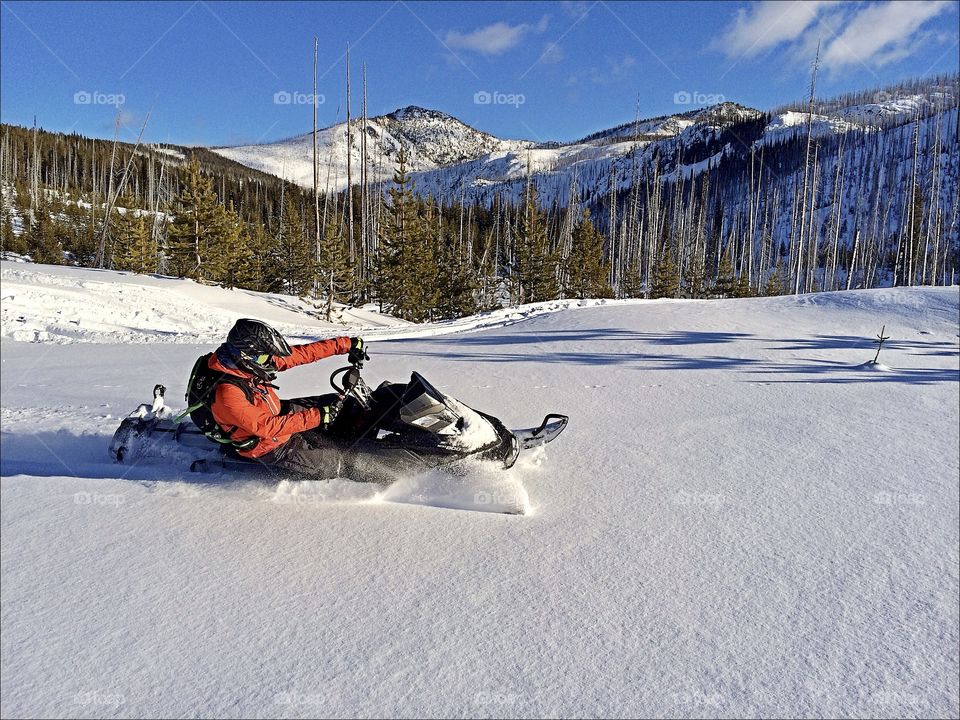 Snowmobiling through deep powder in the Idaho backcountry on a bluebird day. 