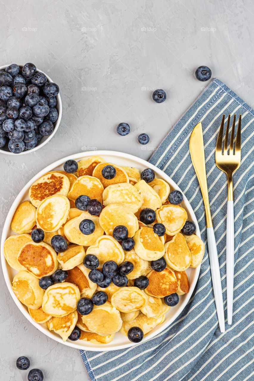 Flat lay of tiny pancakes with fresh blueberries 