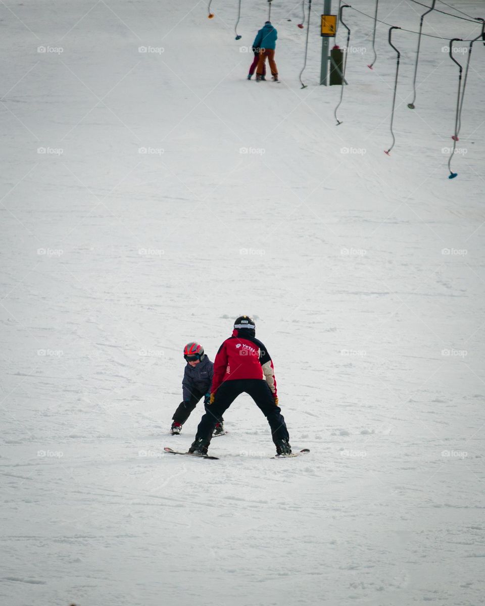 An instructor teaching a kid how to ski