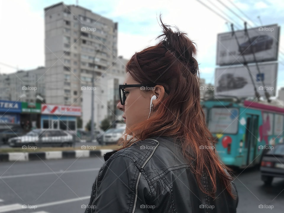 Young woman with red haircut and headphones in the city 