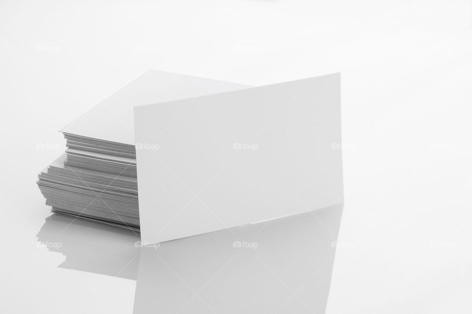 Blank white business cards on white reflective background