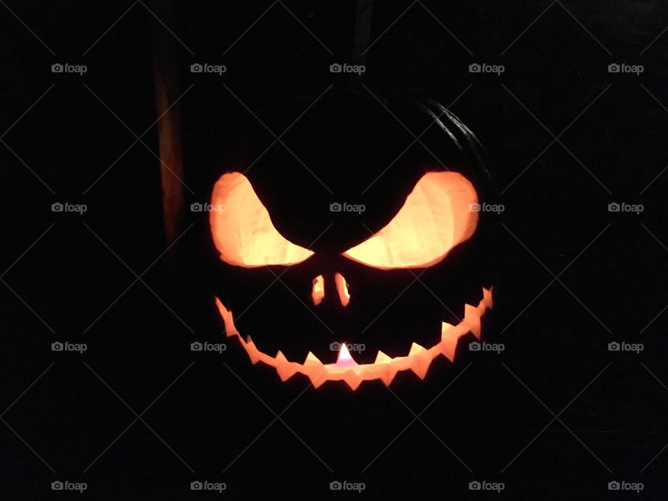 A pumpkin Lit in the darkness with a angry expression